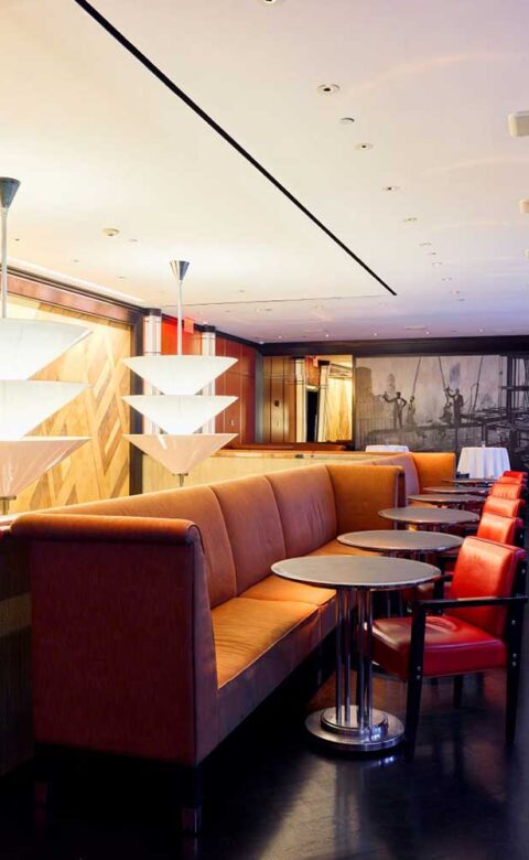 empty tables between a long couch and individual chairs in a bar