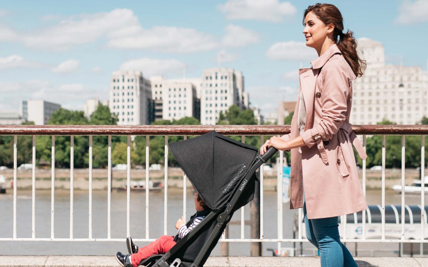 a woman pushing a toddler in a stroller along a waterway