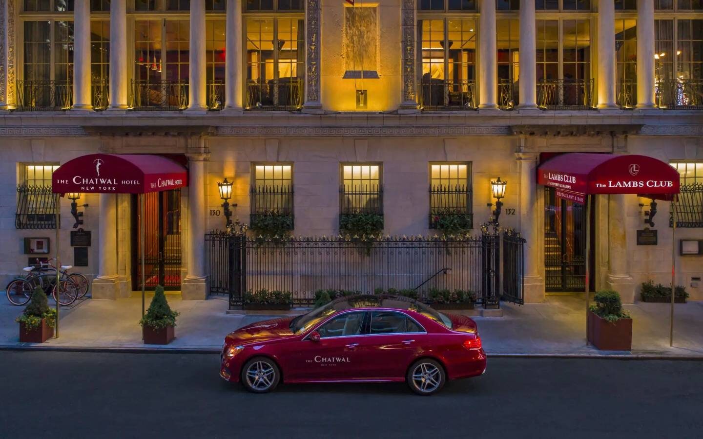 a red car parked in front of a hotel