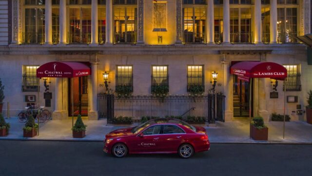 a red car parked in front of a hotel